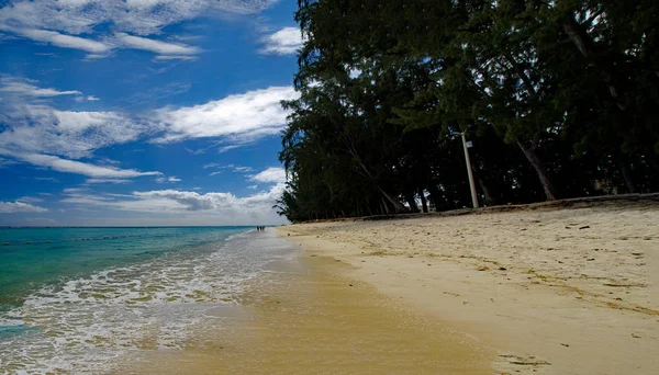 Flic en Flac/Mauritius-20 sierpnia 2018: ludzie w słoneczny dzień chodzenie na publicznej plaży Flic en Flac z tropikalnych drzew na skraju Oceanu Indyjskiego, Mauritius — Zdjęcie stockowe