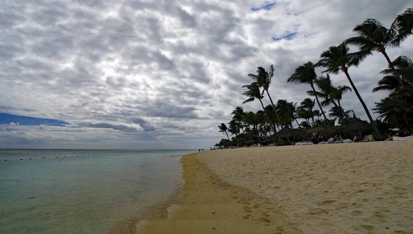 Flic en Flac/Mauritius-20 sierpnia 2018: ludzie w słoneczny dzień chodzenie na publicznej plaży Flic en Flac z tropikalnych drzew na skraju Oceanu Indyjskiego, Mauritius — Zdjęcie stockowe