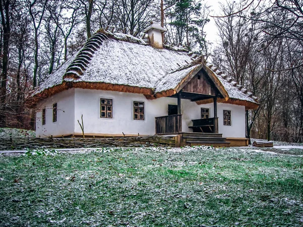 Ukraynalı köy kulübe thatched çatı ile. İlk kar
