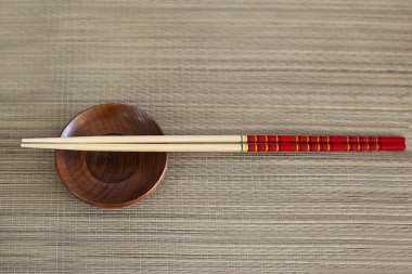 İki ahşap Chopsticks, küçük kahverengi kase ahşap arka planda hizmet vermiştir. Yemek için Asya geleneksel bambu aletleri. Sushi seti. Boşluk 