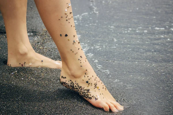 Plajda ayaklar var. Genç kadının ayakları suda yavaşça daldırma. 