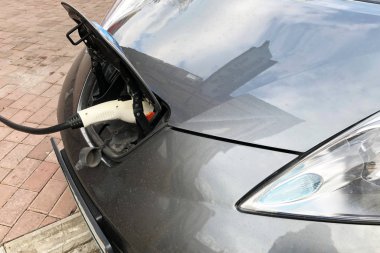 gri bir elektrikli araba şarj işlemi. Elektrikli bir aracın şarj işlemi. Arka plan için elektrikli otomobil soketi, seçici odak