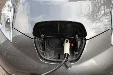 Gri bir elektrikli araç şarj süreci, yakın çekim. Kolay ve ekolojik ulaşım. eko-araba enerji temini süreci