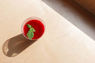 Ahşap bir arka plan üzerinde plastik bir fincan ahududu reçeli ve nane yaprağı ile hindistan cevizi panna cotta Bölümü, plastik bir fincan içinde kondensat damlacıkları, üst vie