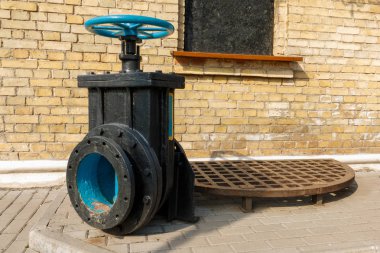 arka planda tuğla duvar ile siyah bodrum üzerinde eski mavi vana. bir sıvının akışını kontrol etmek için mekanik bir cihazdan oluşan kontrol