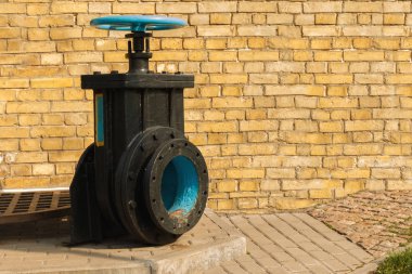 arka planda tuğla duvar ile siyah bodrum üzerinde eski mavi vana. bir sıvının akışını kontrol etmek için mekanik bir cihazdan oluşan kontrol