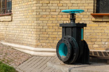 siyah taban üzerinde eski mavi vana, arka planda tuğla duvar. Belirli mekanizmalarda sıvı, buhar veya gaz çıktısını kontrol etmek için bir valf