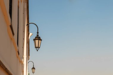 Mavi gökyüzünün arka planına karşı eski kilise duvarının beyaz taş duvar üzerinde eski fenerler, tex için kopya alanı ile dikey görüntü