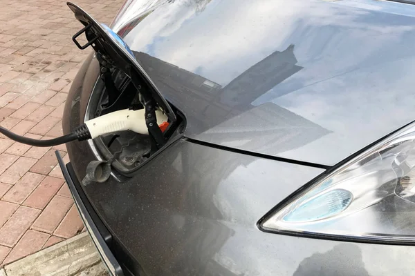 gri bir elektrikli araba şarj işlemi. Elektrikli bir aracın şarj işlemi. Arka plan için elektrikli otomobil soketi, seçici odak