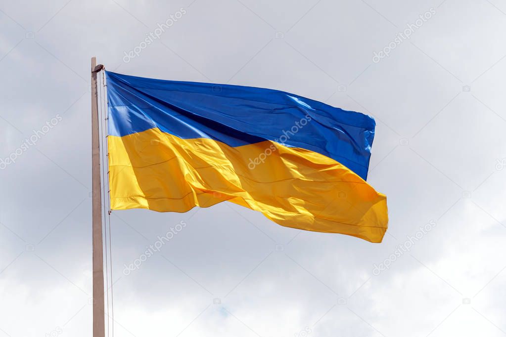 Flag of Ukraine fluttering in the wind on the gray sky background. Blue and yellow Ukrainian national flag on a flagpole against a sky, bottom view. The symbol of 2019 ballot and poll in Ukraine