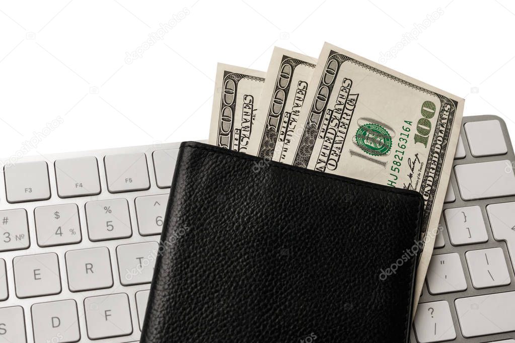 hundred dollar bills in a black passport that lies on the white keyboard, isolated on white. concept purchase of flying tickets via the Internet