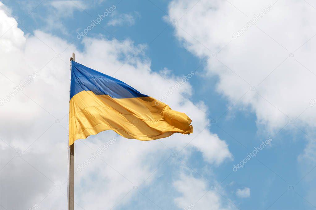 Blue and yellow Ukrainian national flags on a flagpoles against a blue sky, bottom view. The symbol of 2019 ballot and poll in Ukraine, space for text