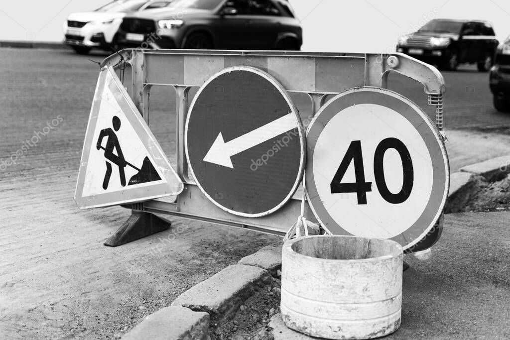 Road marking on the road, warning signs. Direction of detour, sign speed limit 40 and roadworks, monochrome shot