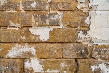 Beyaz eski boya duvardaki sarı tuğlaları soyar.