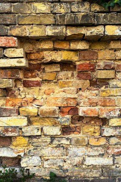 old wall of a crumbling castle. various antique stones make up the wall in the street, vertical image