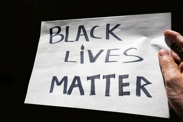 Black Lives Matter hand sigh on the black background. cardboard banner "black lives matter"