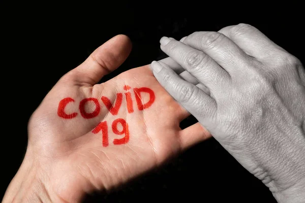 a woman shakes hands with a man who has covid-19 written on his hand. transmission of the virus through handshake