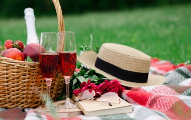 Piknik detayları, ekoseli kırmızı şarap bardakları, meyveler ve meyve bardakları, kitaplar.