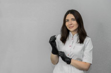 Beyaz üniformalı güzellik uzmanı ofiste siyah tek kullanımlık eldiven giyer. Şablon. Yüksek kalite fotoğraf