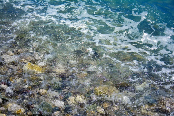Meersalzwelle, Wasser bedeckt die Kieselsteine an der Küste, Steine — Stockfoto