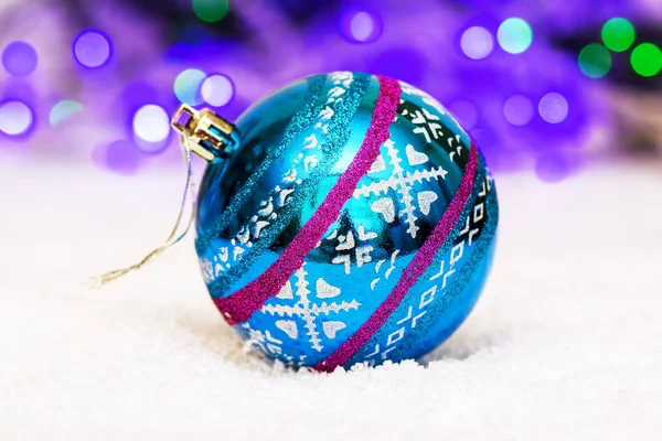 Όμορφη μπάλα για διακόσμηση χριστουγεννιάτικο δέντρο βρίσκεται στο τεχνητό χιόνι σε φόντο bokeh — Φωτογραφία Αρχείου