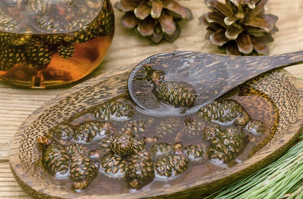 Delicioso engarrafamento de jovens cones de abeto em uma xícara de madeira e uma colher de madeira — Fotografia de Stock