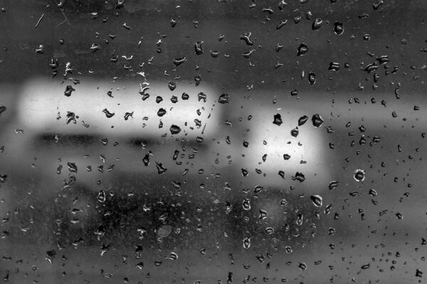fuzzy machine on the glass background with rain drops. black and white photo. degradation