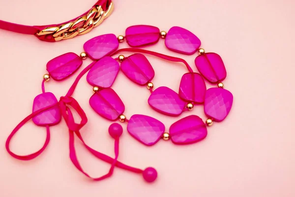 Fashionable pink accessories - beads, lipstick, belt on a gentle pink background. flay lay.