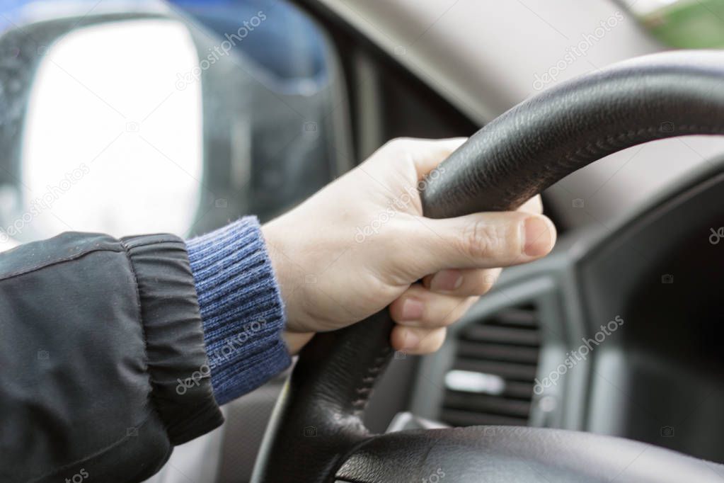 Brutal men's hands hold the steering wheel in the car on the road. close-up.
