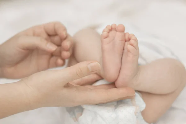 母の手は優しく手のひらに生まれたばかりの赤ちゃんの足を保持します。 — ストック写真