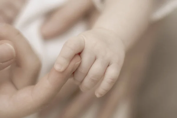 Zachte aanraking van de handen van moeders en pennen van een pasgeboren baby. Close-up. Vervagen — Stockfoto