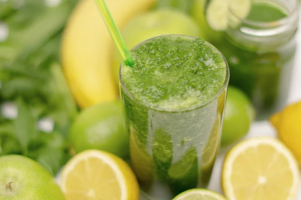 Smoothie verde em uma taça de vidro cercado por vegetais verdes e frutas para a saúde, dieta e perda de peso, vegetarianismo. Fecha. borrão . — Fotografia de Stock