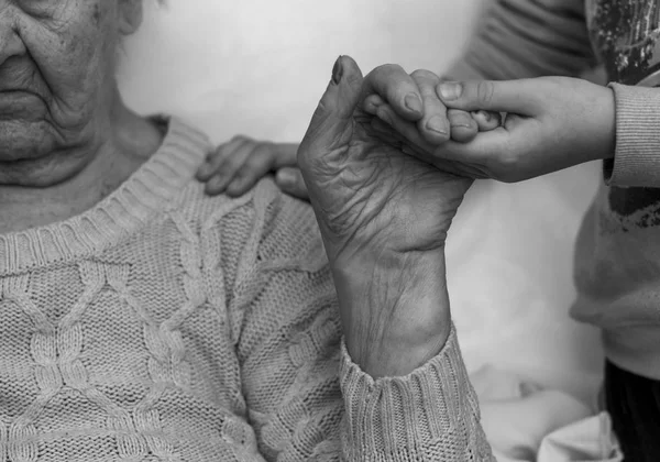 Urenkel kümmert sich liebevoll um kranke alte Großmutter im Krankenhaus. Schwarz-Weiß-Foto — Stockfoto