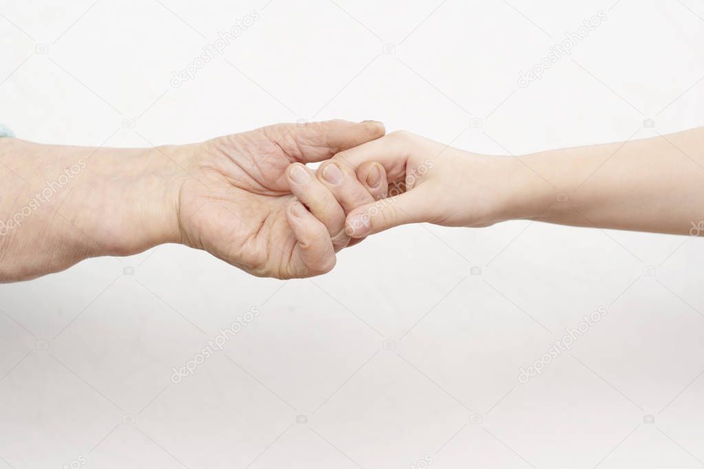 the hands of an old man and a child holding each other on a white background. contrast. idea