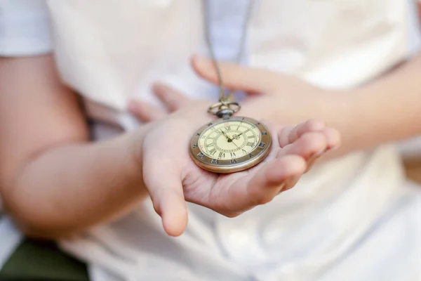 A boy in a white shirt holding in the palm of a vintage retro watch on a chain — Stock Photo, Image