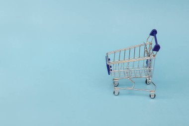 mavi bir arka plan üzerinde metal bir alışveriş sepeti küçük bir kopyası. kopya alanı