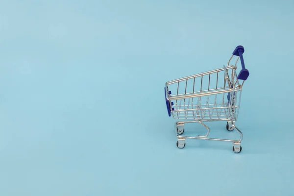 mavi bir arka plan üzerinde metal bir alışveriş sepeti küçük bir kopyası. kopya alanı