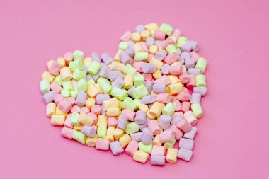 Pembe bir arka planda ihale çok renkli Marshmallow hava lezzetli romantik kalp