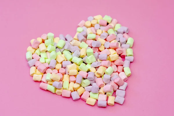Pembe bir arka planda ihale çok renkli Marshmallow hava lezzetli romantik kalp
