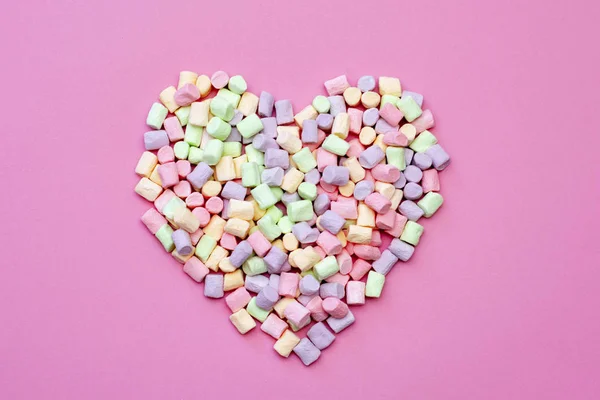 Pembe bir arka planda ihale çok renkli Marshmallow hava lezzetli romantik kalp