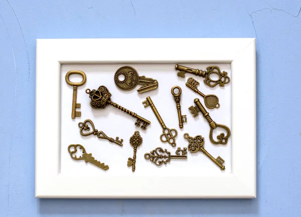 Zabytkowe klucze o różnym kształcie i konfiguracji w białej ramce obrazu na białym tle na niebieskim tle — Zdjęcie stockowe