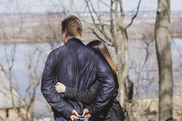 Amar a los hombres y mujeres de pie, sin rostro, en un abrazo y mirar la hermosa naturaleza primaveral — Foto de Stock