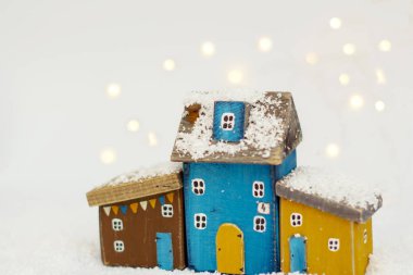 Beyaz karla kaplı arka planda doğal ahşap el yapımı İskandinav Noel rahat oyuncak evler. Minimalizm.