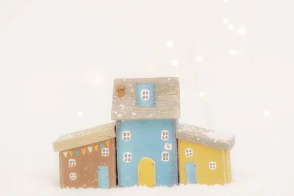 Σκανδιναβικά Χριστουγεννιάτικα φιλόξενα σπιτικά παιχνίδια φτιαγμένα από φυσικό ξύλο χειροποίητα σε λευκό χιόνι καλυμμένο φόντο. Μινιμαλισμό. Φωτογραφία Αρχείου