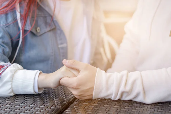 Hände eines jungen glücklichen Paares, das sich an einem sonnigen Tag in einem Straßencafé hält. — Stockfoto