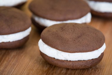 Whoopie turta ya da ay pasta, çikolata kek krem buzlanma ahşap arka plan ile dolu tatlılar