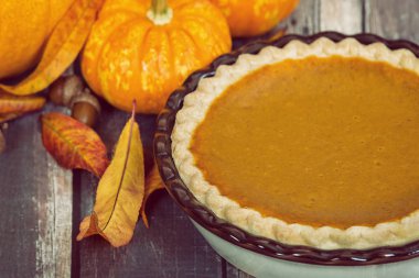 Kabak pasta kabak, altın sonbahar yaprakları ve meşe palamutları, rustik masada.