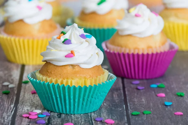 Cupcakes coloridos decorados com polvilhas em forma de coração — Fotografia de Stock