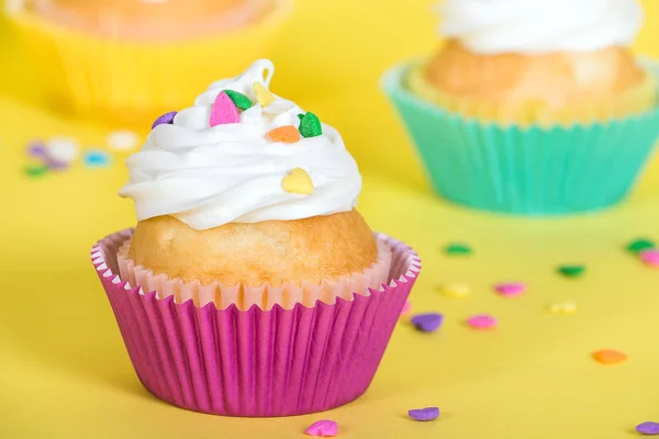 Cupcakes coloridos decorados com polvilhas em forma de coração — Fotografia de Stock