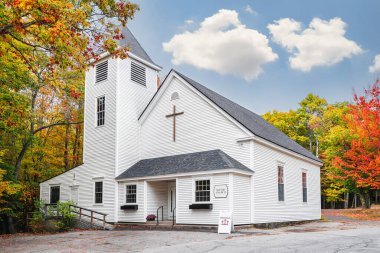 Beyaz ülke Baptist kilisesi New England 'da sonbaharda güzel yeşillik renkleriyle çevrilidir. Beyaz bulutlar ve mavi gökyüzü arkaplanı.